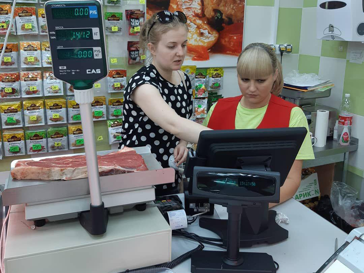 Продавец взвешивает мясо и бьёт чек на сенсорной кассе